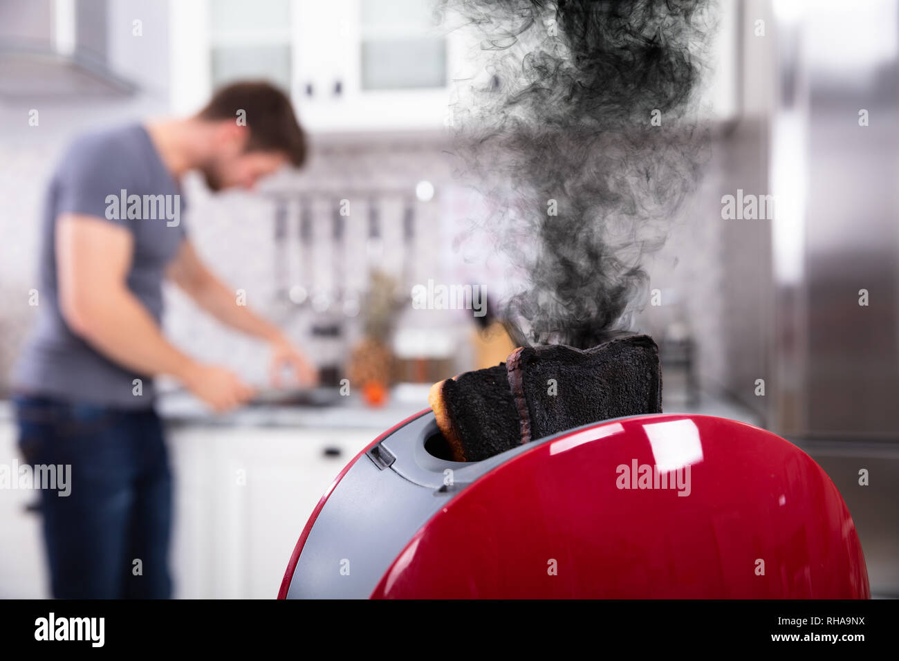 Nahaufnahme einer Rot Toaster mit verbrannten Toast Während man Schneiden von Gemüse in der Küche Stockfoto