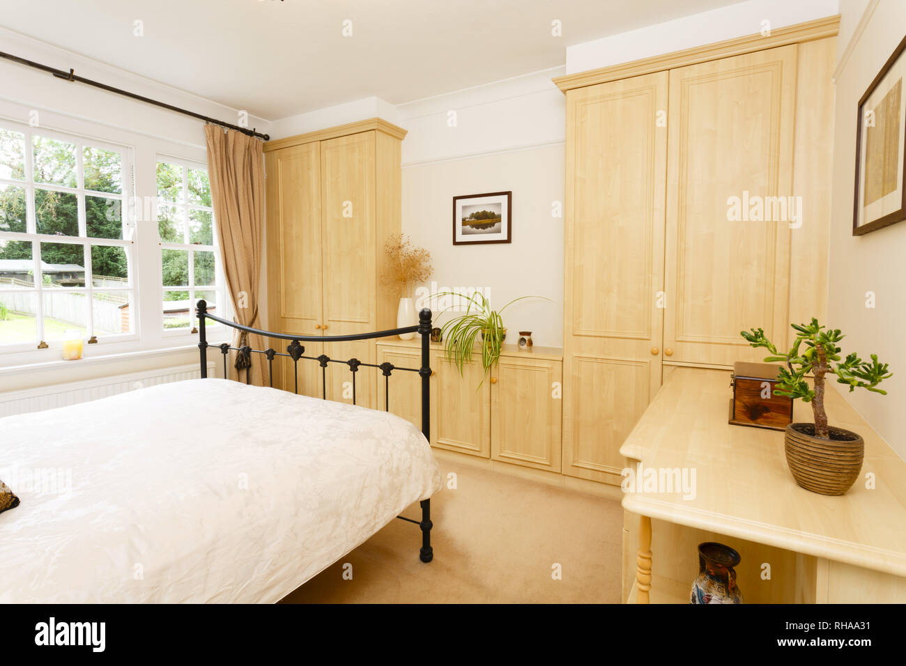 Modernes Schlafzimmer mit neutralen Farben, Gusseisen Doppelbett und Einbauschränken Stockfoto