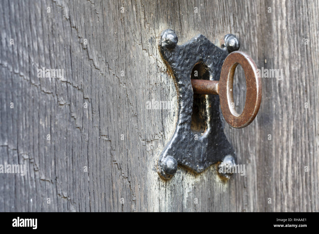 Nahaufnahme von einem alten Schlüssel in einem traditionellen Schlüsselloch sperren und alte Holztür Stockfoto
