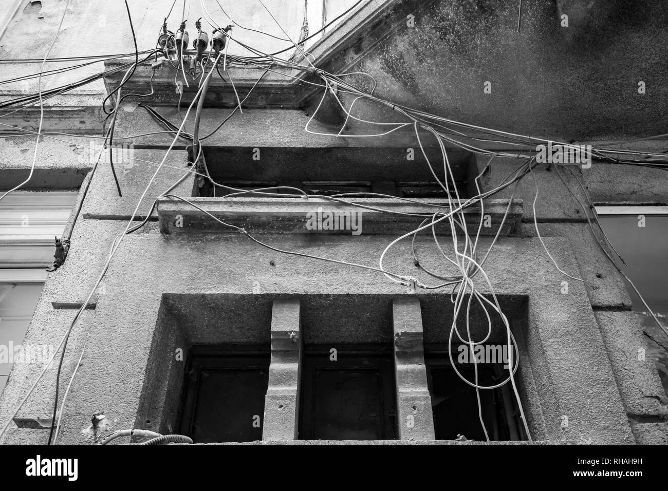 Chaotische Kabel Management der installierten elektrischen und optischen Kabeln am Wohnhaus in Sofia, Bulgarien. Schwarz/Weiß-Kontrast Stockfoto