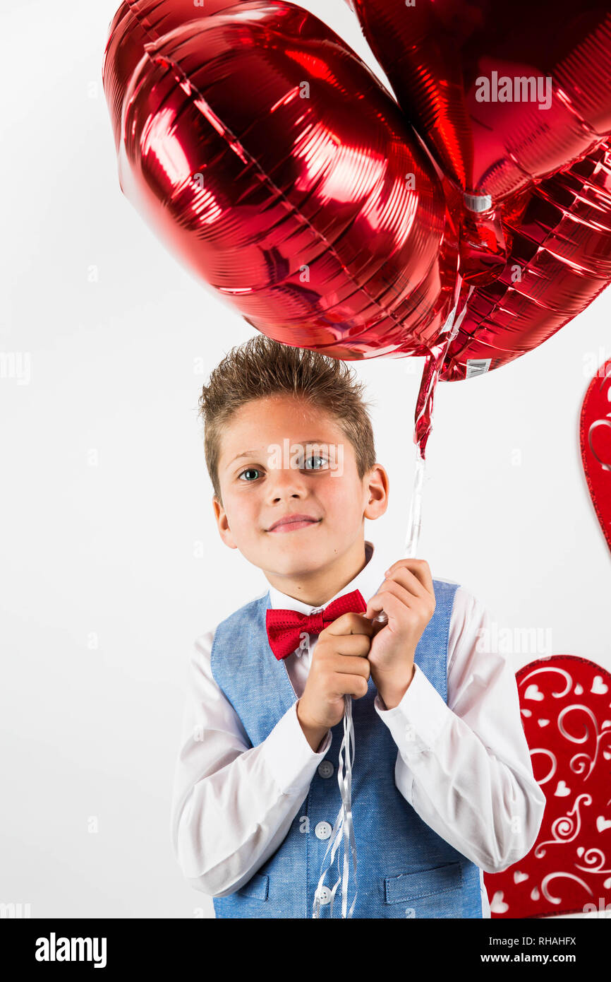 Saint Valentine's Day. Stattliche Herr Junge mit blauen Hemd, rote Krawatte, rote Rosen Schaufel und rote Luftballons. Valentines Tag Kinder. Liebe und Freundschaft. Stockfoto