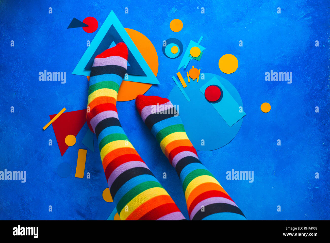Mädchen Beine in Regenbogen gestreifte Socken auf einen farbigen Hintergrund mit Colour-blocking einfache Formen. Abstrakte Geometrie flach Stockfoto