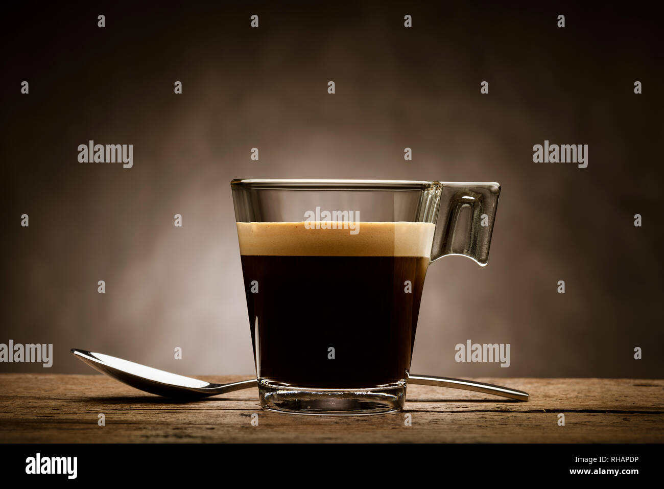 Schwarzen Kaffee im Glas Schale mit Teelöffel auf hölzernen Tisch Stockfoto