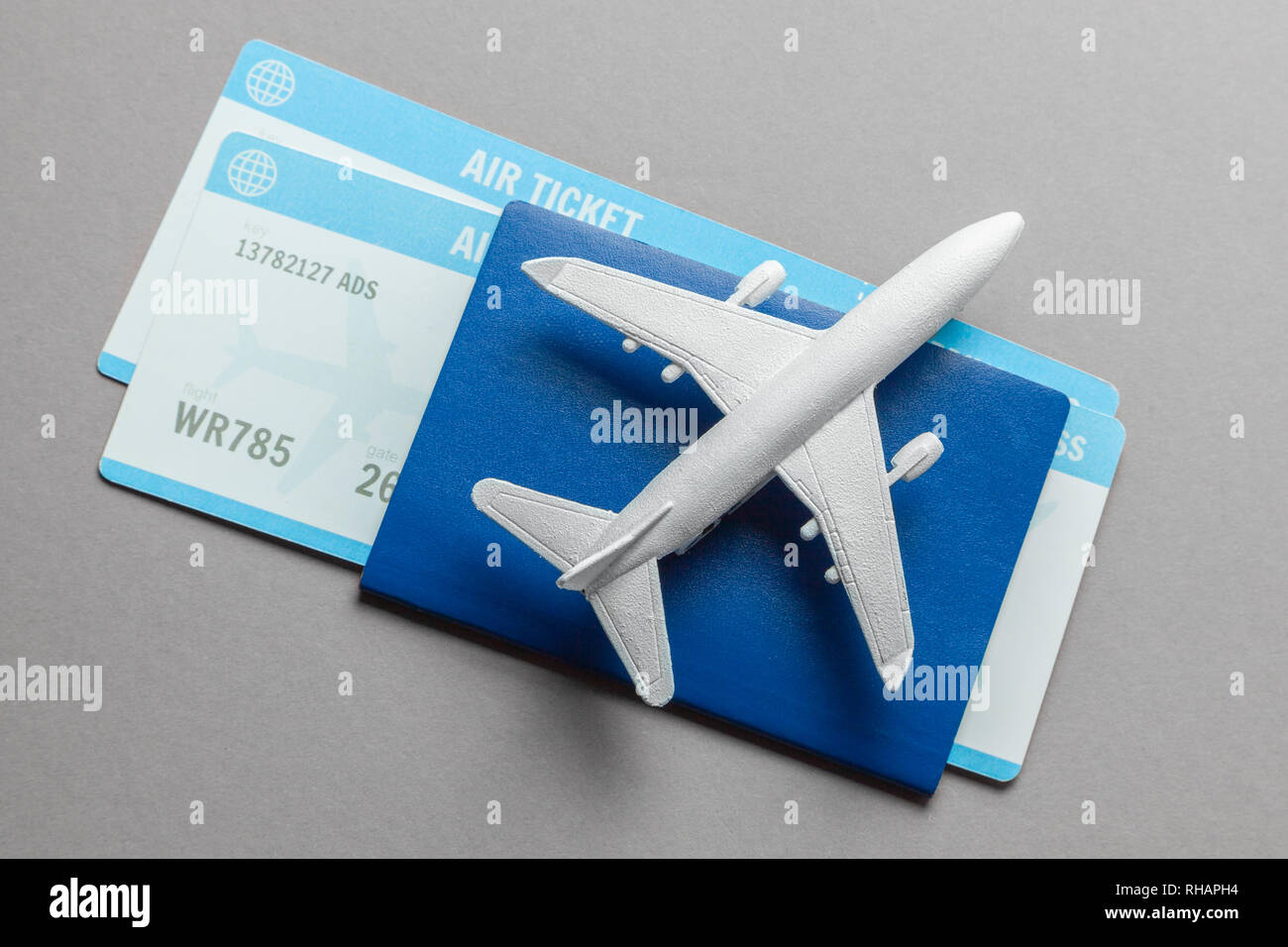 Tickets für Flugzeug und Reisepass mit Modell der Passagiermaschine auf grauem Hintergrund. Stockfoto