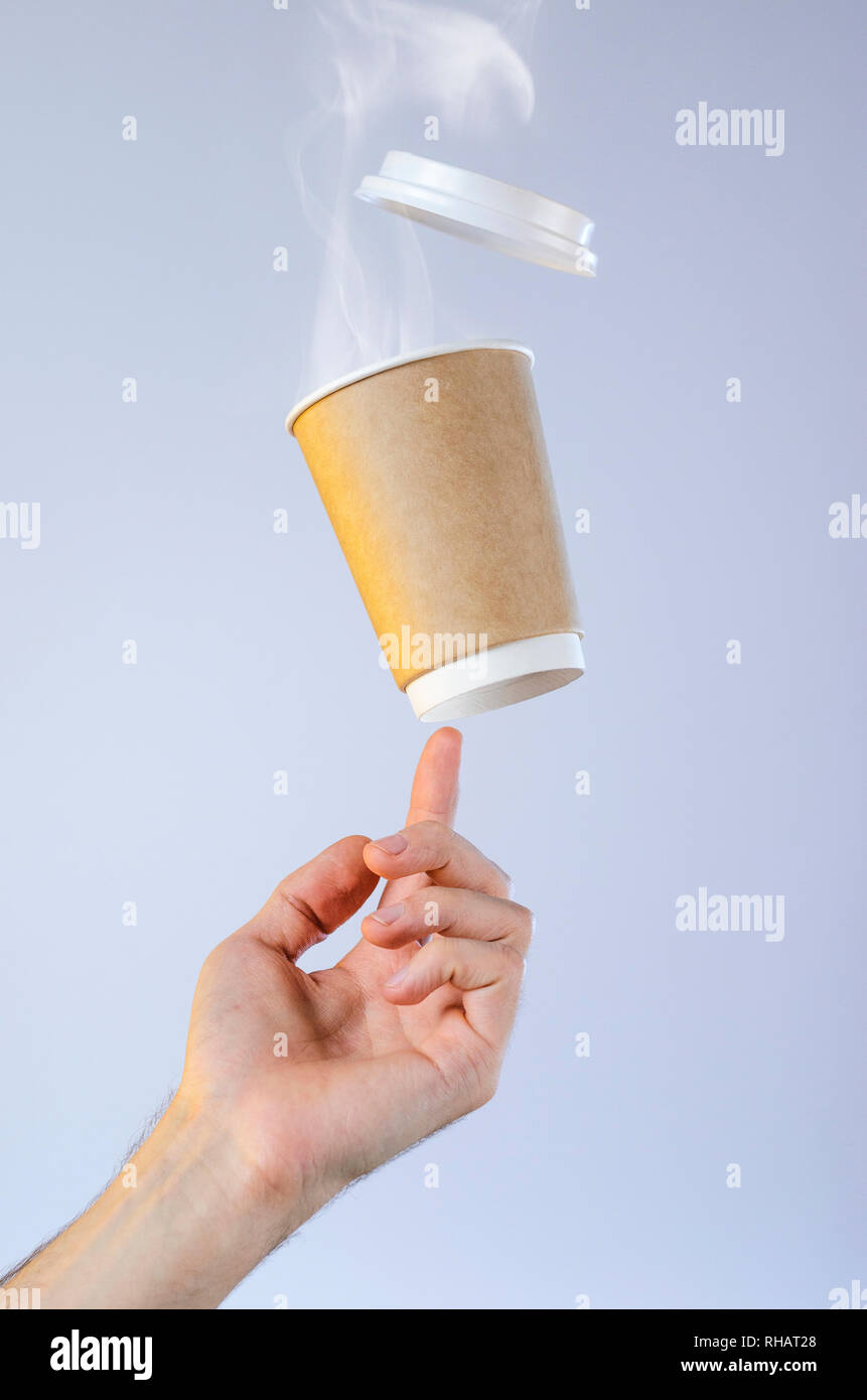 Eine Tasse mit heißem Kaffee und eine Wolke von Dampf Salden auf der Fingerspitze. Frei schwebende Schale aus Kunststoff Deckel. Kaffeepause Konzept. Leeren platz für Stockfoto