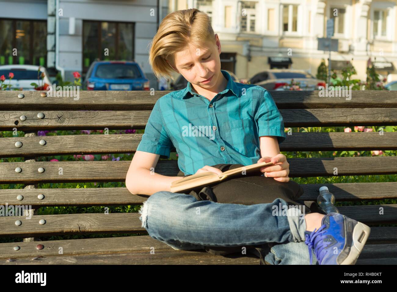 Outdoor Portrait eines halbwüchsigen Jungen und Mädchen 14, 15 Jahre alt, sitzt auf der Bank im Stadtpark mit Buch Stockfoto