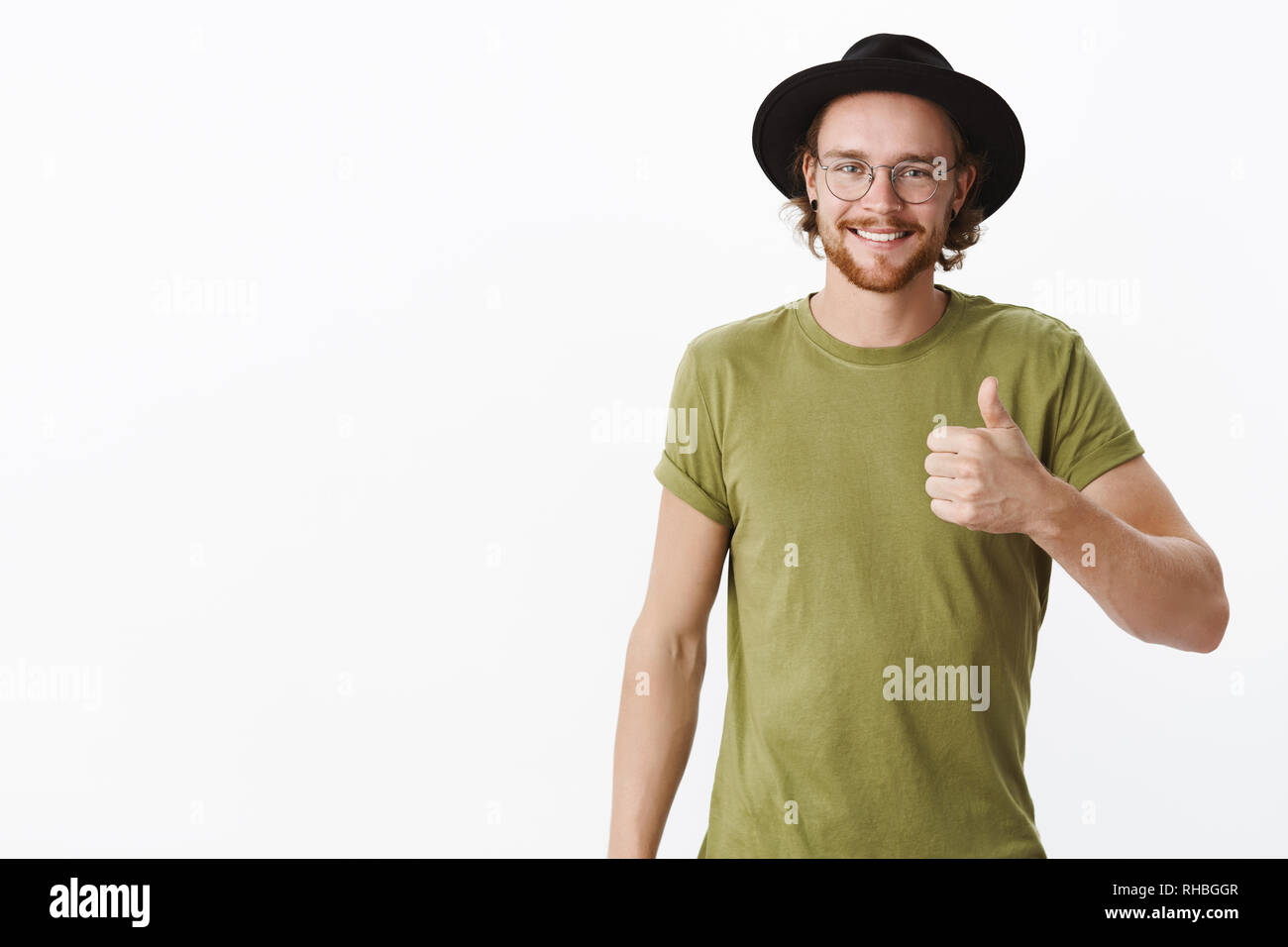 Halten Sie das Tun groß. Portrait von Stolz und zufrieden charismatische junge Mann mit Bart und durchbohrt die Nase in Brille und Hut geben Daumen bis in Stockfoto