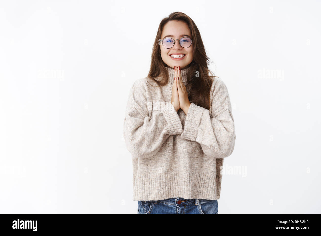 Portrait von charmanten Dumme flirty Girl in Gläsern und Pullover, Hände halten, beten in der Nähe der Brust und breit lächelnd wie bitten, betteln Freund Stockfoto