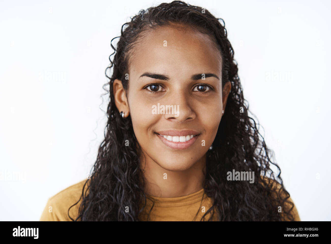 Headshot junger schüchtern und freundlich glücklich Afrikanisch-amerikanische Frau mit lockigem Haar lang freudig lächelnd von der Kamera begeistert und optimistisch, als Stockfoto