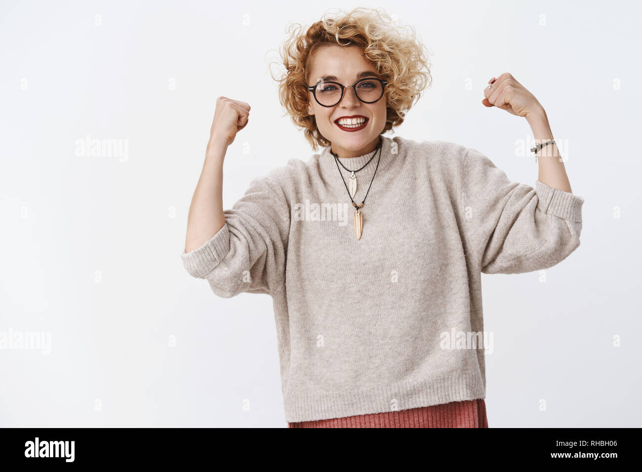 Ja Girl Power. Stolz und glücklich, zufrieden, gut aussehende upbeat Mädchen in Gläsern und Pullover die geballten Fäuste in Sieg und Feier lächelnd Stockfoto