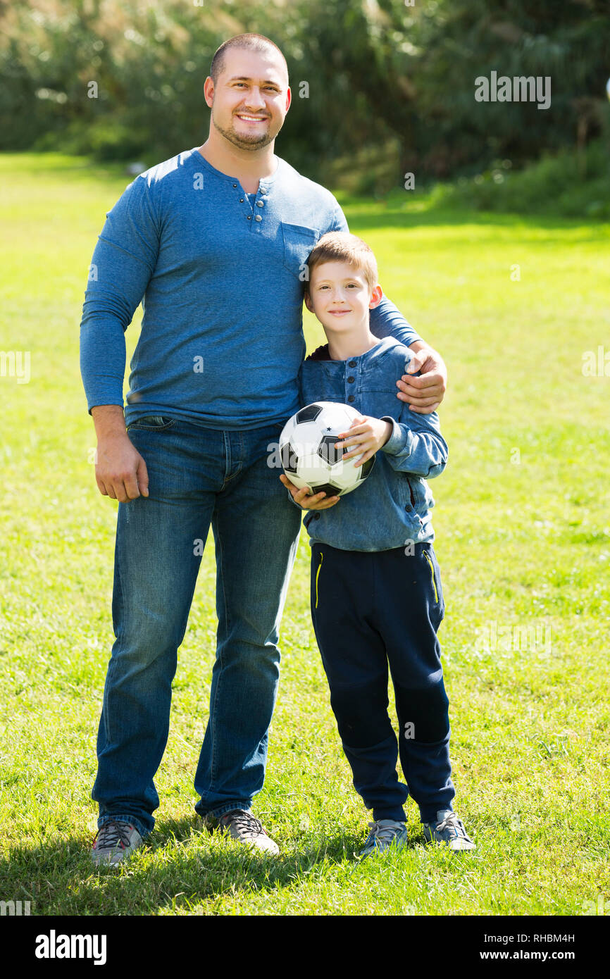 Porträt der glückliche junge Vater und Sohn mit Fußball auf Gras Stockfoto
