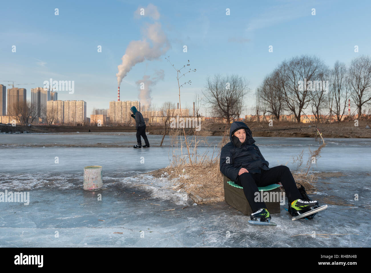 Mann mit Schlittschuhen auf einer Eisbahn am Ufer der SongHua Fluss ausruhen, Jilin Stadt Stockfoto