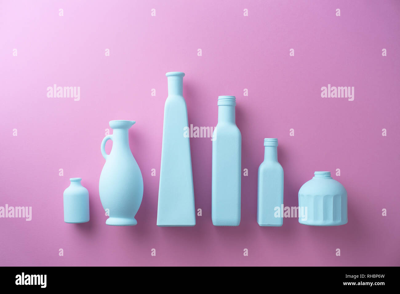 Bunt bemalten Glas Flaschen in einer Reihe über rosa Hintergrund organisiert Stockfoto