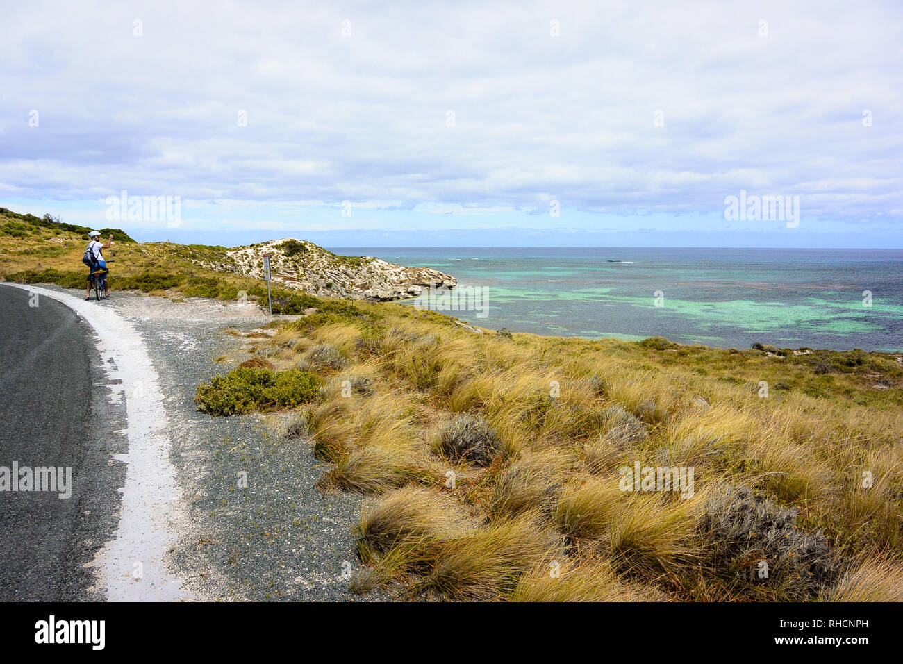 Mit dem Fahrrad auf der Seite der Straße, ein Tourist wird über sein Smartphone Bilder von den idyllischen grünen und blauen Meer Wasser Paradies Rottnest nehmen Stockfoto