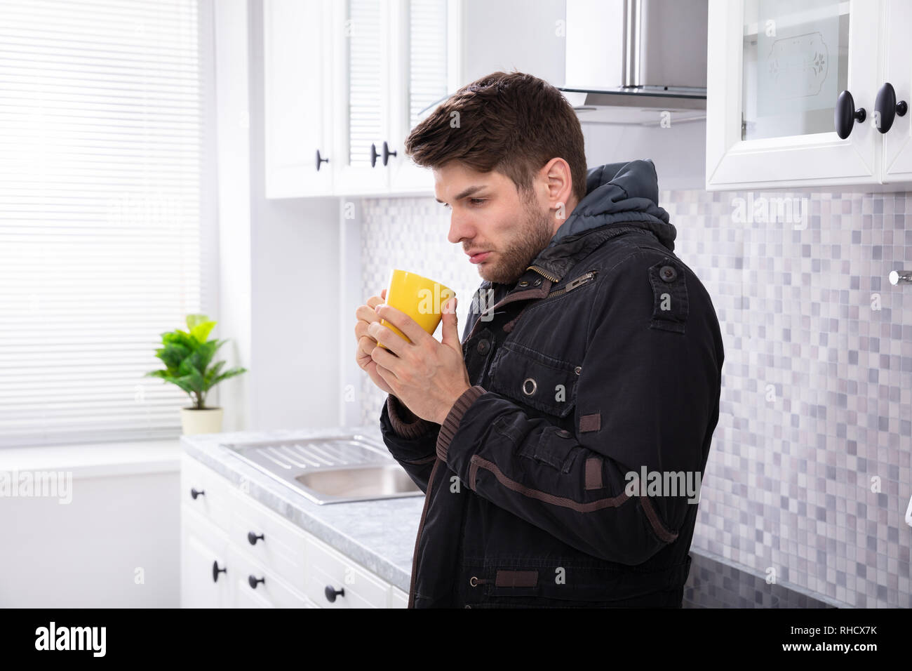 Seitenansicht des kranken Mann trinkt Kaffee in der Küche Stockfoto