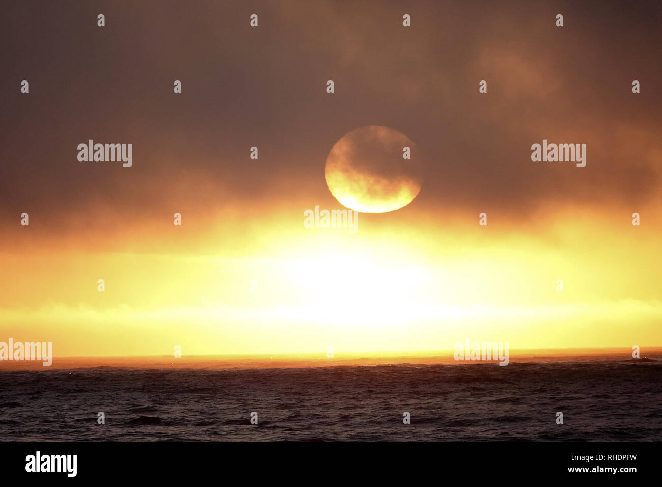 Die Sonne im Hazel Nebel Wolken setzt der Westen über den Pazifischen Ozean. Stockfoto