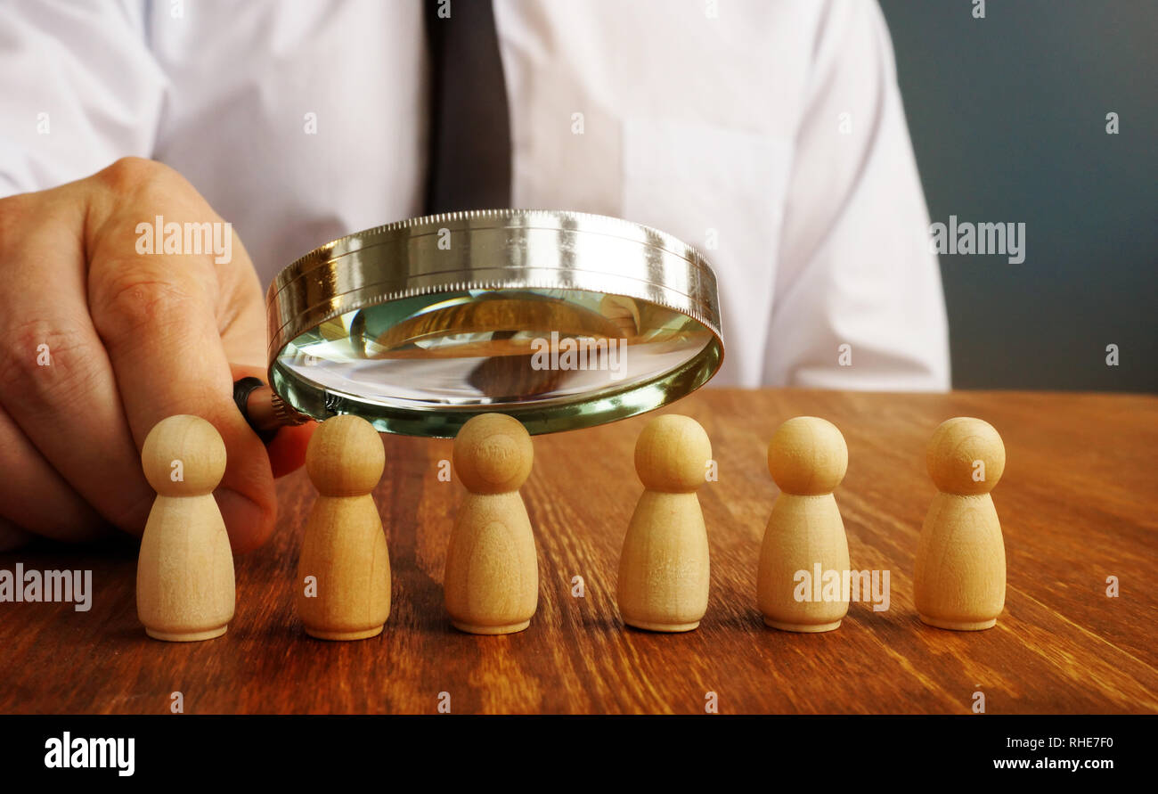 Performance Review. Mann mit Lupe Figuren als Symbol der Mitarbeiter bewerten. Stockfoto