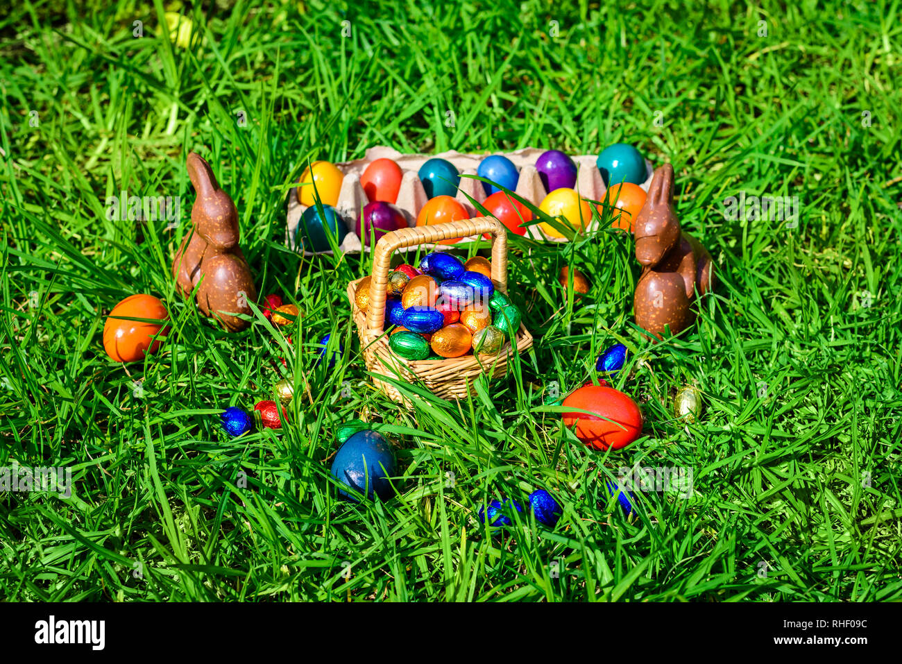 Schokolade Osterhasen, Stroh Korb voll bunter Eier auf grünem Gras Stockfoto