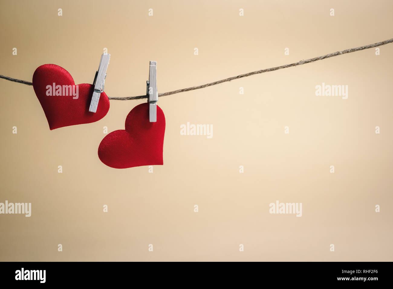 Paar entzückende rote Herzen hängen von einer Zeichenfolge durch Holzpflöcke. Der Valentinstag Szene mit kopieren. Stockfoto