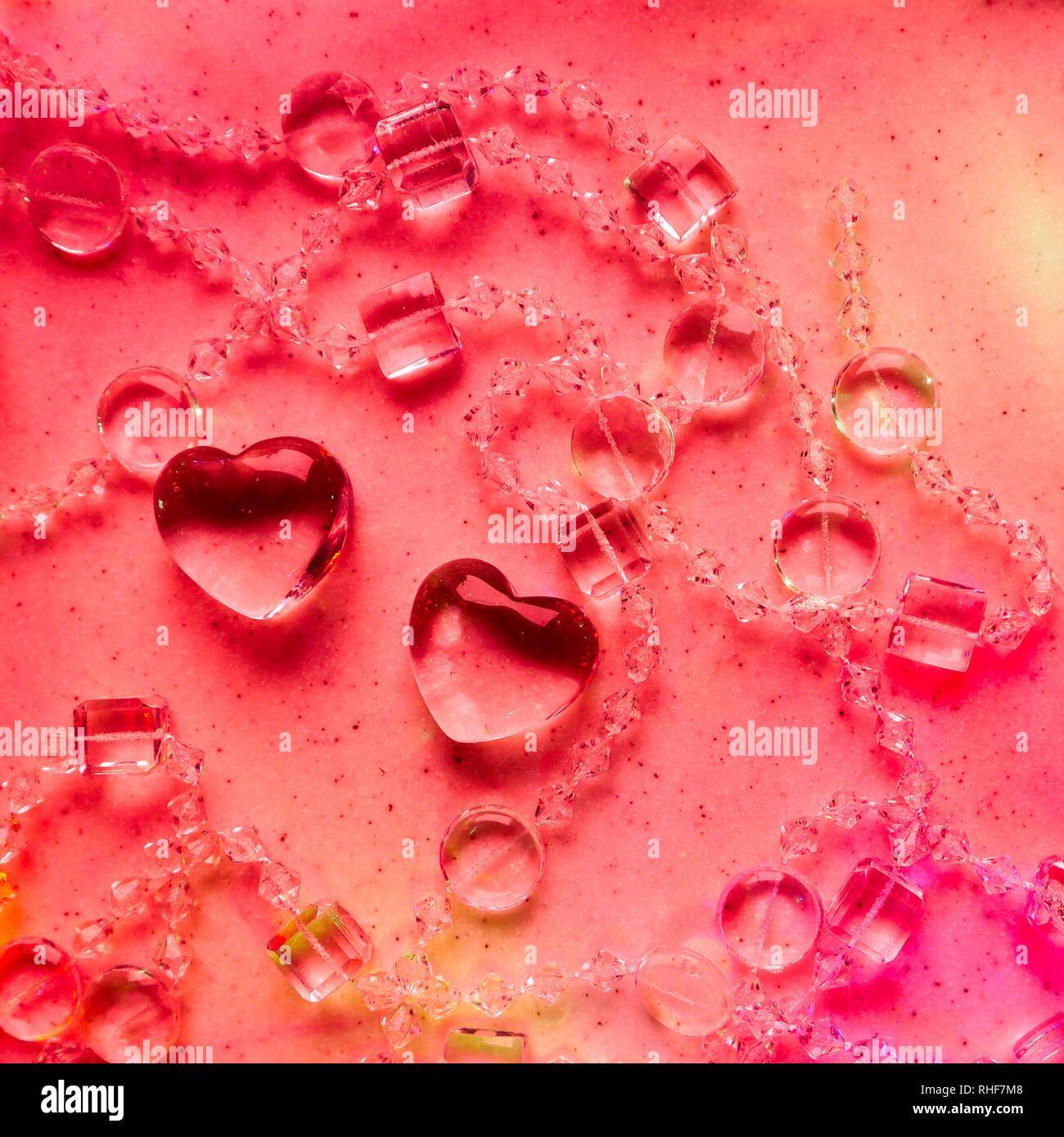 Transparente Herzen und Perlen auf Marmor in rosa Ton. Perfekte Valentinstag Grußkarte Hintergrund. Stockfoto