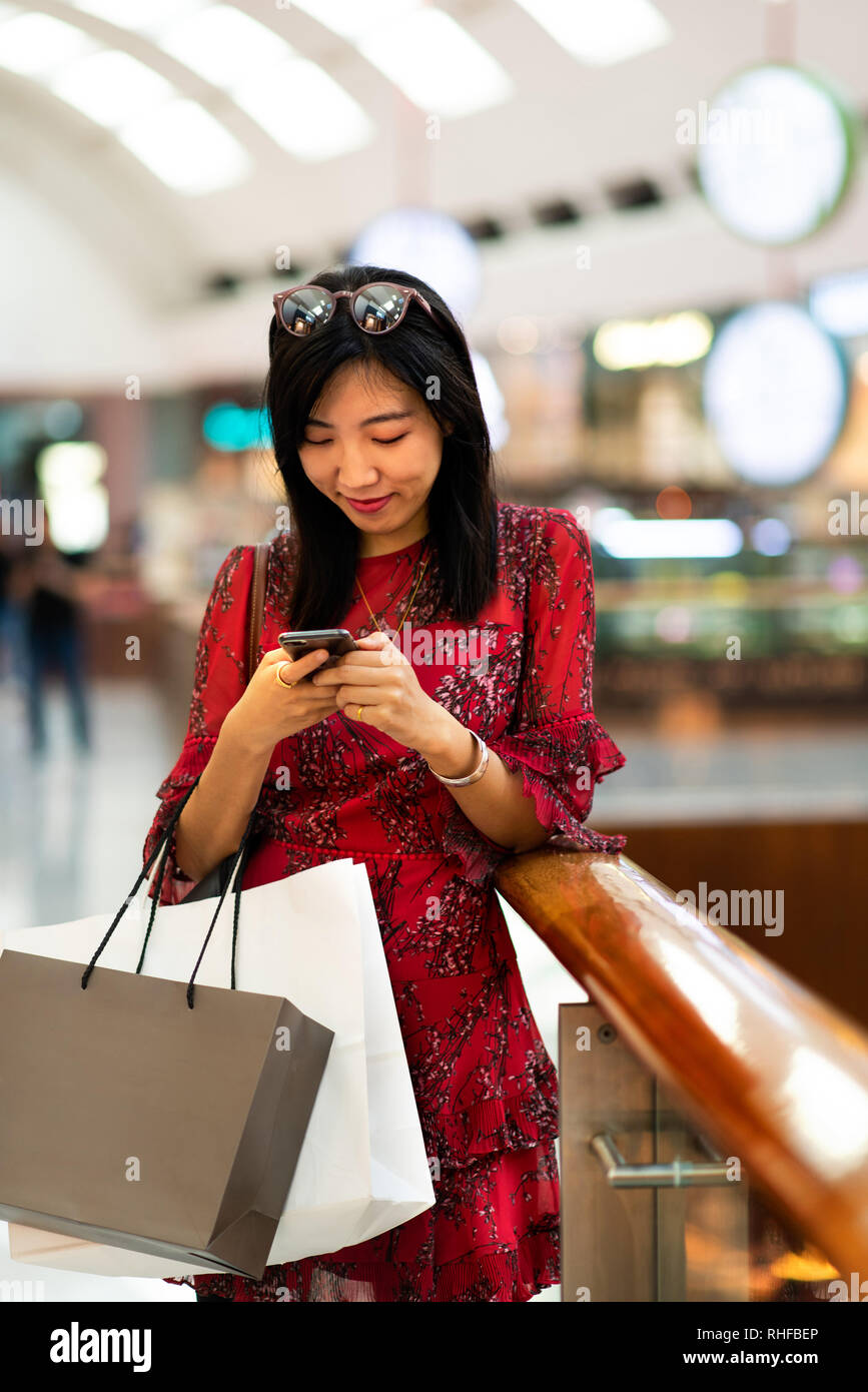 Asiatische Frau mit Phone in einem Einkaufszentrum Stockfoto