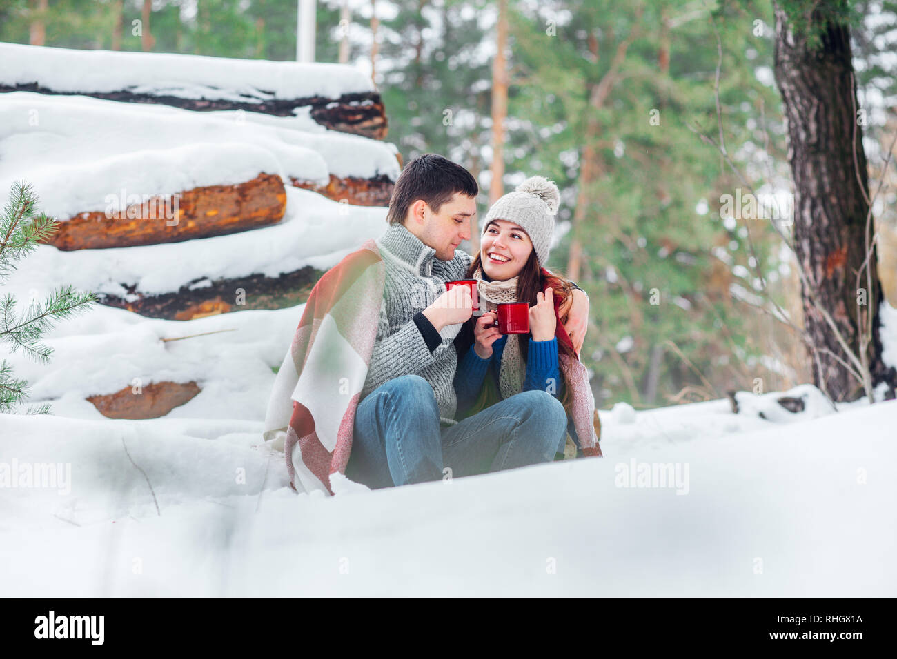 Lächelnden jungen Paar mit cups im Snow park sitzen. Trinken Sie heiße Getränke, Spaß zu haben. Stockfoto