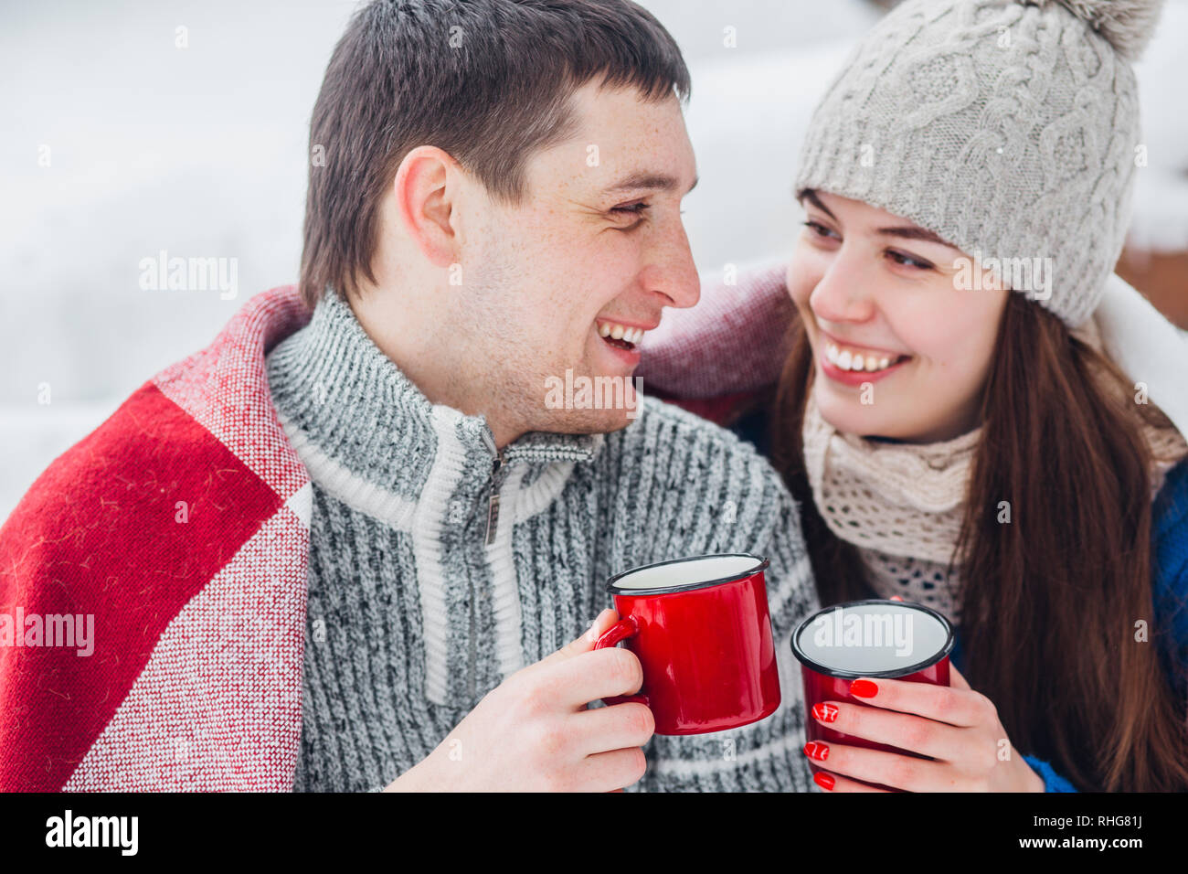 Lächelnden jungen Paar mit cups im Snow park sitzen. Trinken Sie heiße Getränke, Spaß zu haben. Stockfoto