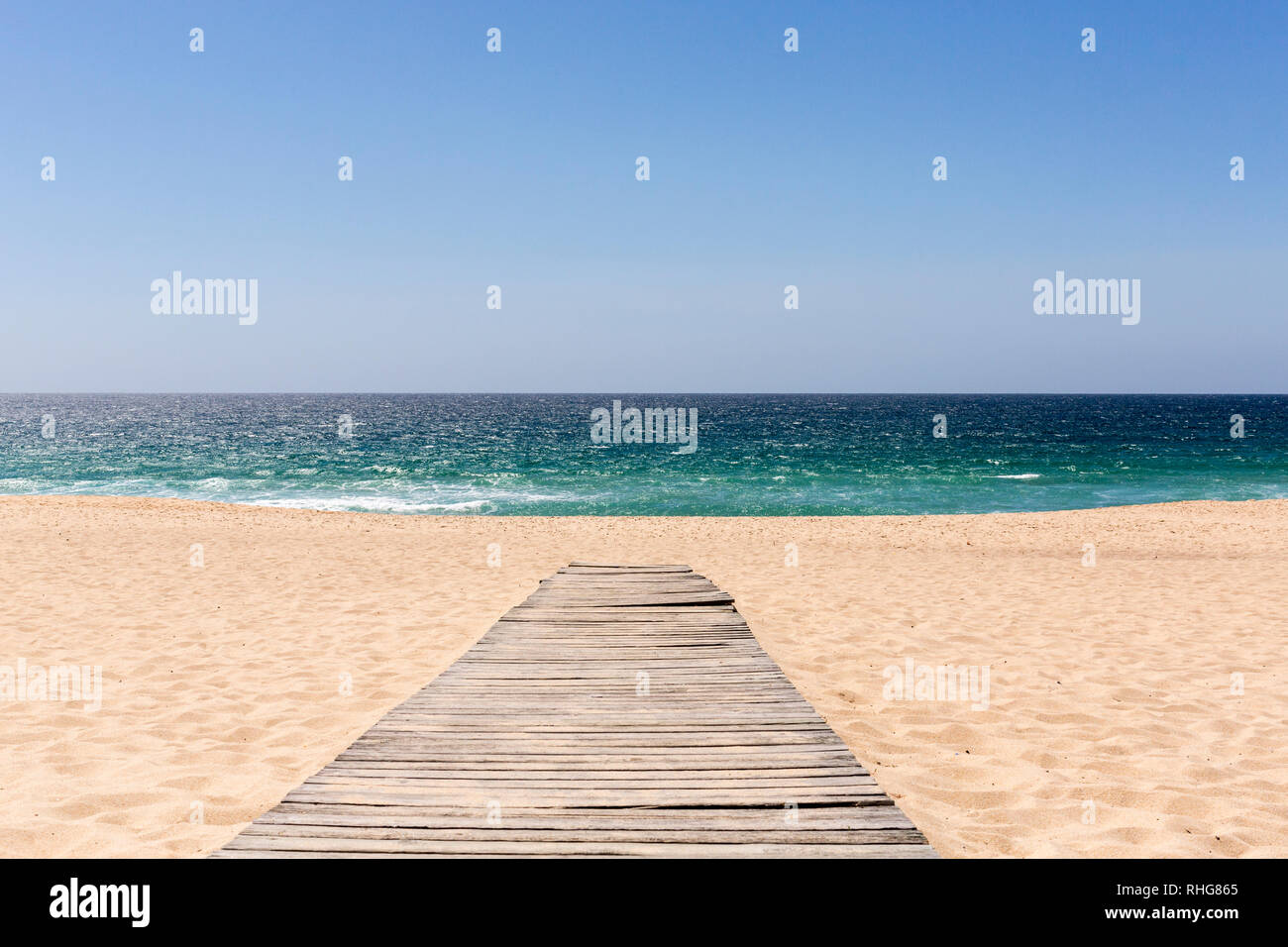 Holzsteg führt zu einem Sandstrand und das Meer mit blauem Himmel Stockfoto