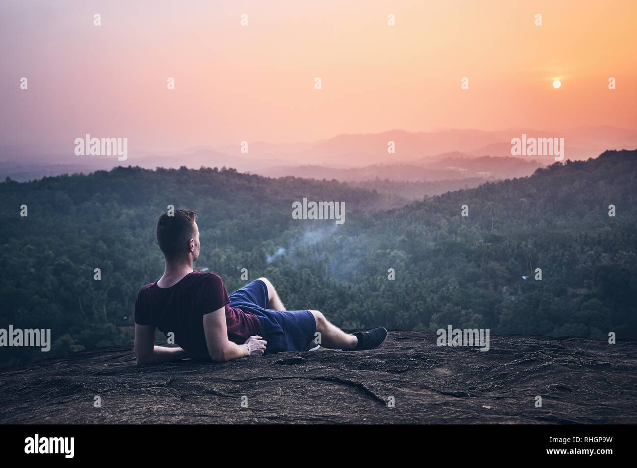 Junger Mann Kontemplation auf der Oberseite des Rock. Landschaft bei Sonnenuntergang in Sri Lanka. Stockfoto
