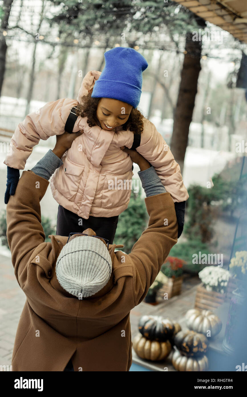 Vater tragen braune Fell sein kleines Mädchen auf seinen Händen halten Stockfoto
