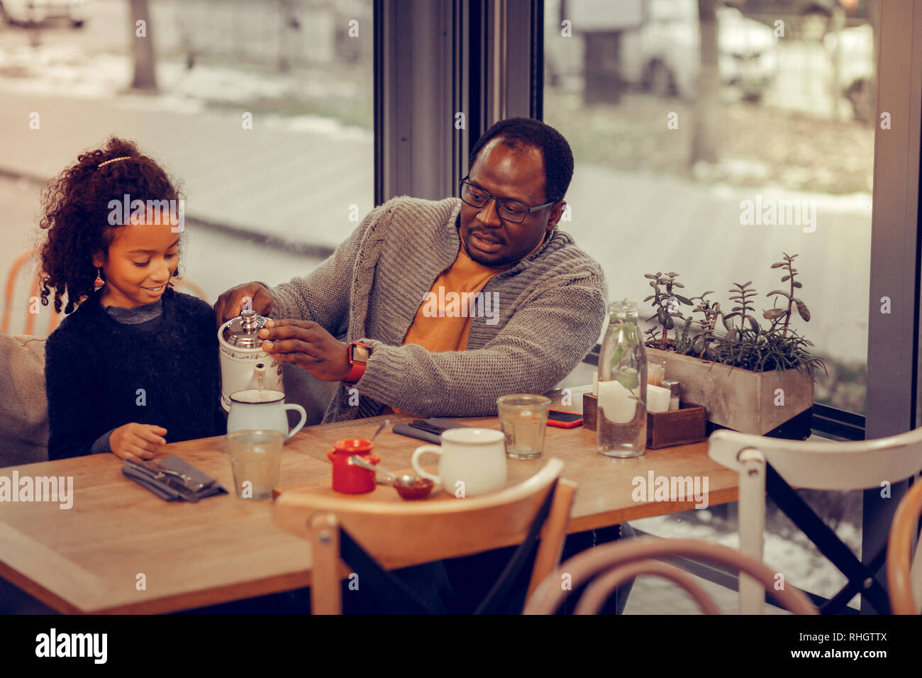 Liebevoller Vater kümmert sich um seine Tochter strömenden heißen Tee für Ihr Stockfoto