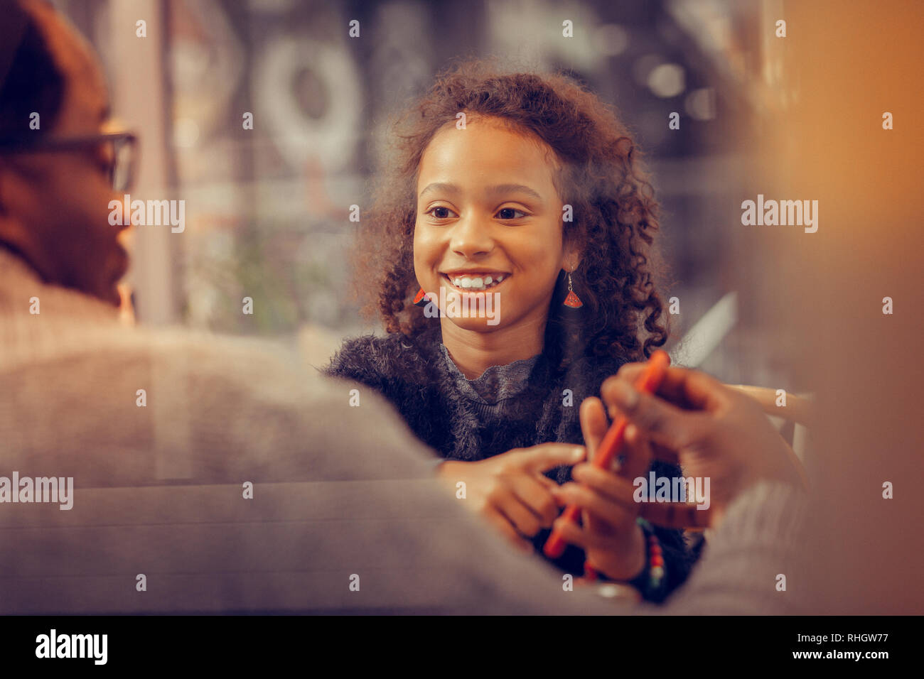 Curly fröhliches Mädchen Gefühl glücklich halten red Smartphone Stockfoto