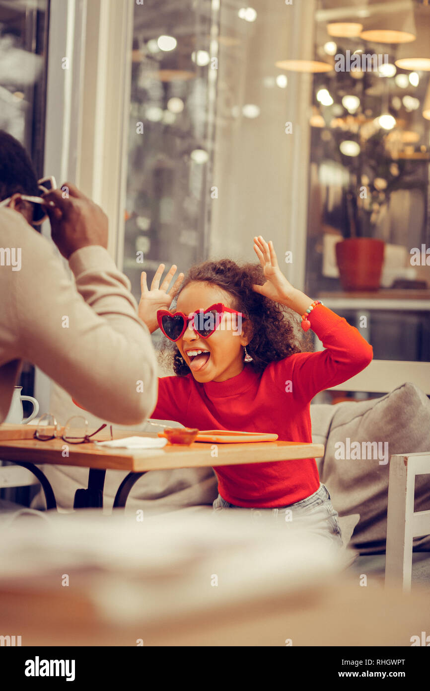 Süße Tochter tragen rote Sonnenbrille Tricks spielen mit ihrem Vater. Stockfoto