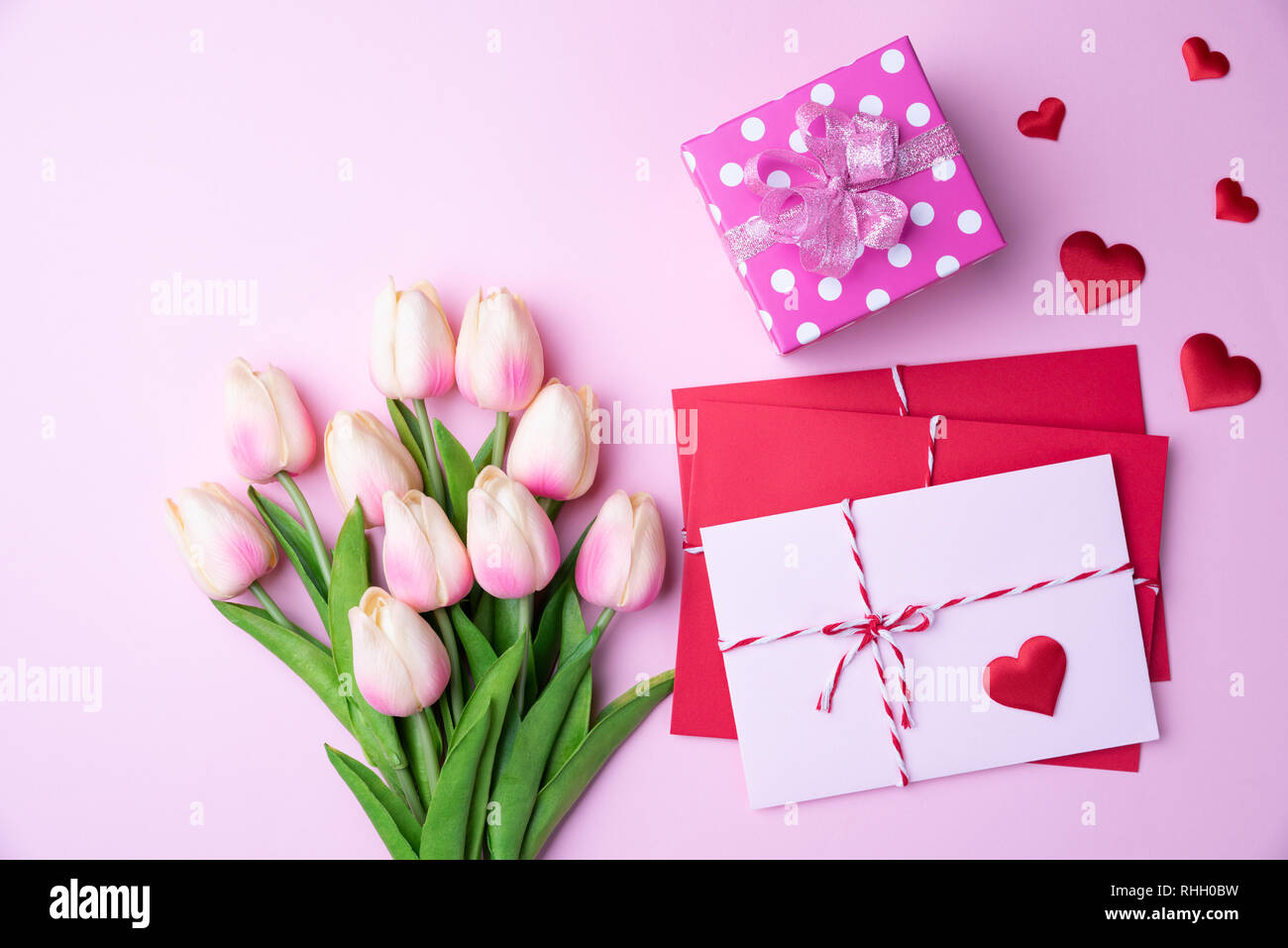 Valentines Tag und liebe Konzept. Rosa Tulpen, Geschenkbox mit roten Herzen und rot rosa Anschreiben auf rosa Hintergrund. Stockfoto