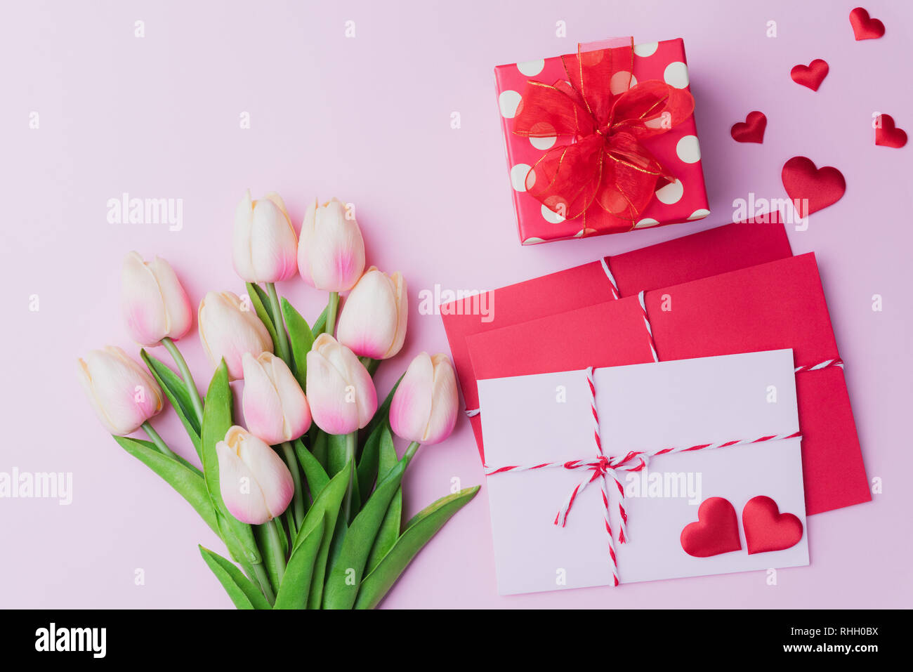 Valentines Tag und liebe Konzept. Rosa Tulpen, Geschenkbox mit roten Herzen und rot rosa Anschreiben auf rosa Hintergrund. Stockfoto