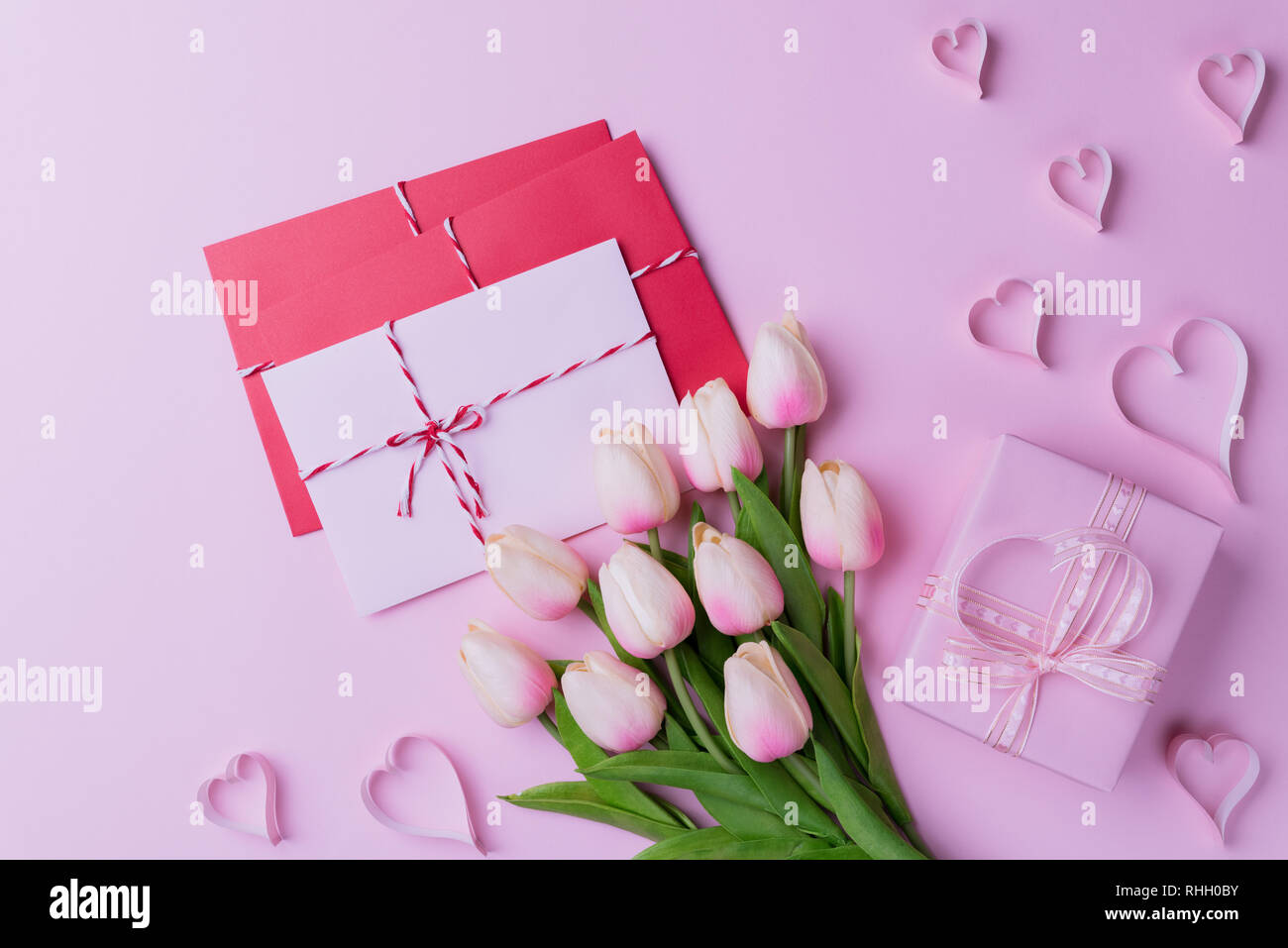 Valentines Tag und liebe Konzept. Rosa Tulpen, Geschenkbox mit Herz und rot rosa Anschreiben auf rosa Hintergrund. Stockfoto