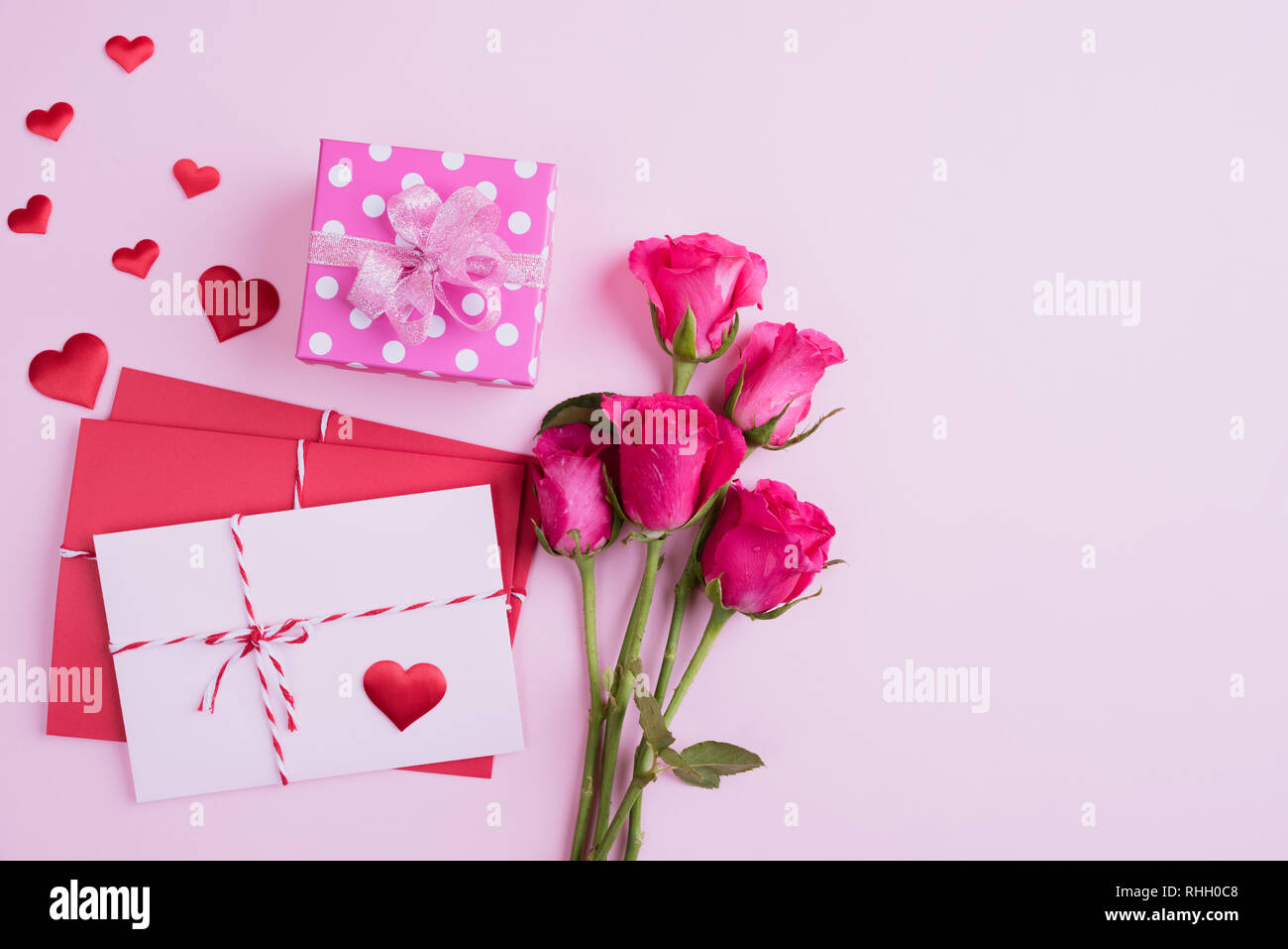 Valentines Tag und liebe Konzept. Rosa Rosen, Geschenkbox mit roten Herzen und rot rosa Anschreiben auf rosa Hintergrund. Stockfoto