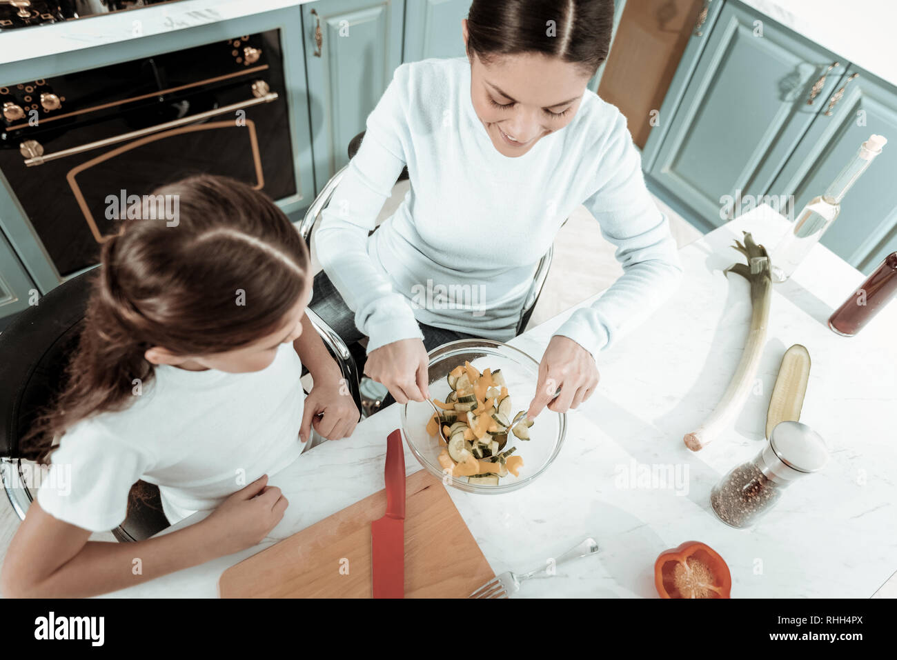 Fröhliche Mutter und Tochter kochen ein neues Gericht zusammen Stockfoto