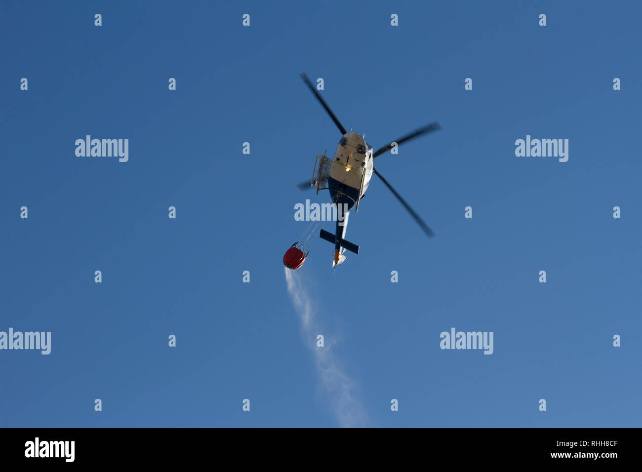 Hubschrauber Löschmittel Waldbrände, Überschrift zu einem Feuer das Verschütten von Wasser aus einem Korb transportiert. Stockfoto