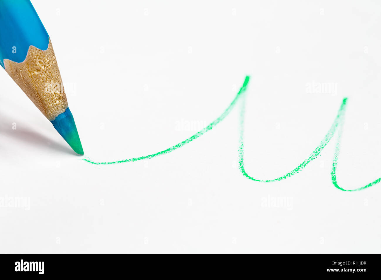 Blau Bleistift zeichnet eine Wellenlinie in Grün. Close-up. Konzept Stockfoto