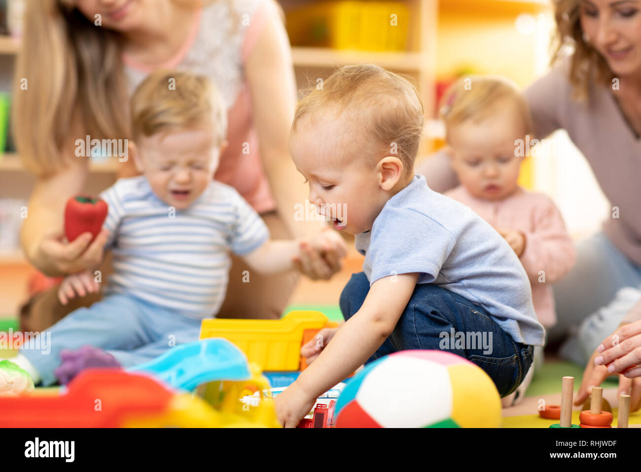 Babys mit Mammen spielen in Day care center Stockfoto