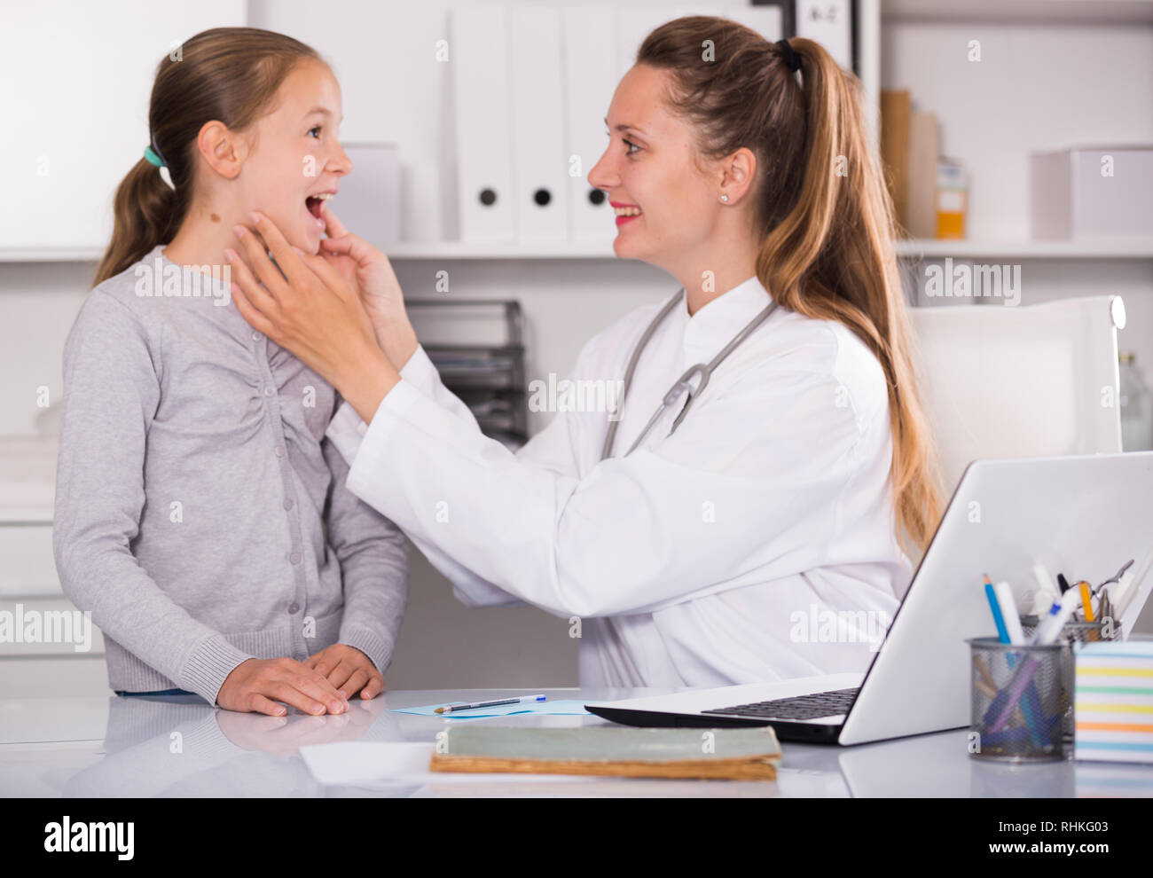 Junge Frau Doktor suchen Bei sick Kehle kleines Mädchen im Medical Center Stockfoto
