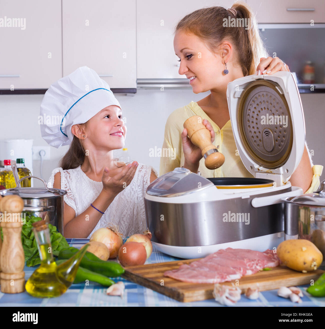 Kleines Mädchen hilft Mama Kochen Gemüse und Fleisch in multicooker in  Küche Stockfotografie - Alamy
