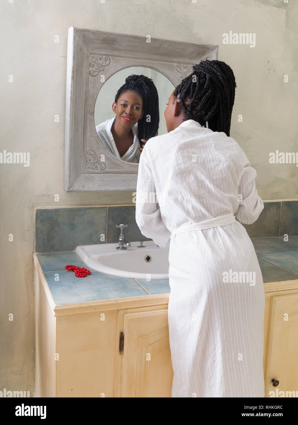 Hübsche junge afrikanische amerikanische Frau, die Ihre morgendliche Routine zu tun vor dem Badezimmerspiegel Stockfoto