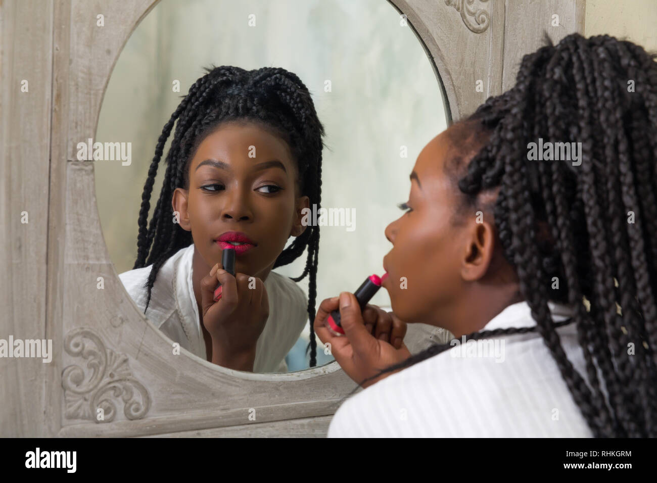 Hübsche junge afrikanische amerikanische Frau, die Ihre morgendliche Routine zu tun vor dem Badezimmerspiegel Stockfoto