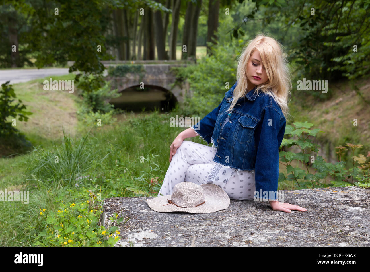 Junge hübsche blonde Frau mit Vintage Hut warten auf rustikalen Brücke Stockfoto