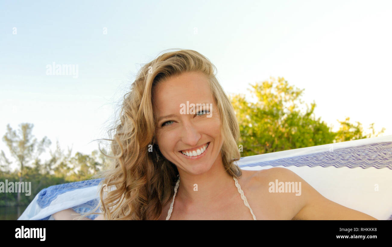 Portrait einer jungen normal blonde Frau glücklich und mit blauen Augen lächelnd in die Natur mit einem weißen und blauen Mandala Schal Stockfoto