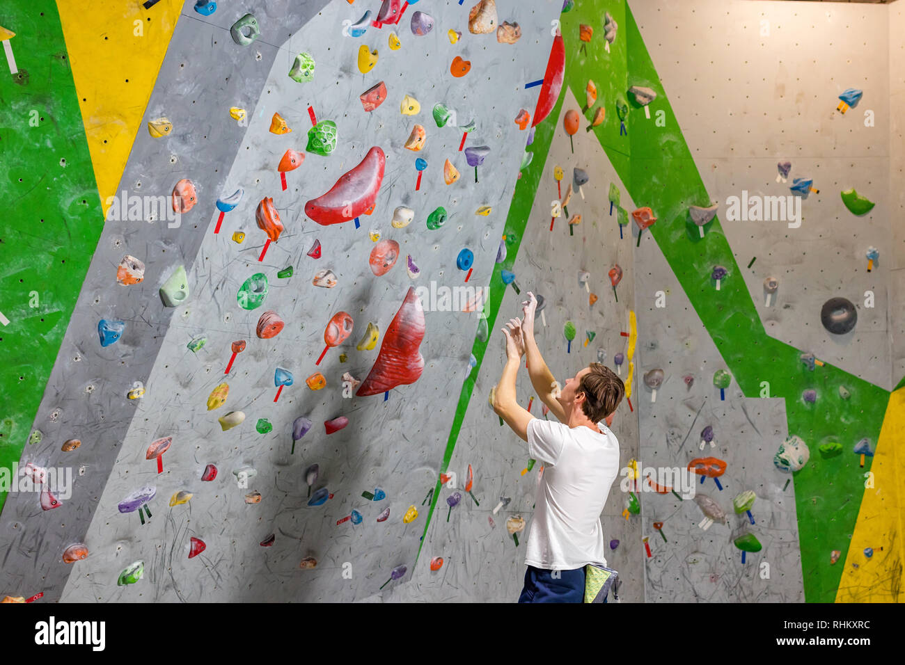 Kletterer erforscht und entwickelt eine Route auf einer Kletterwand im Boulder Halle Stockfoto