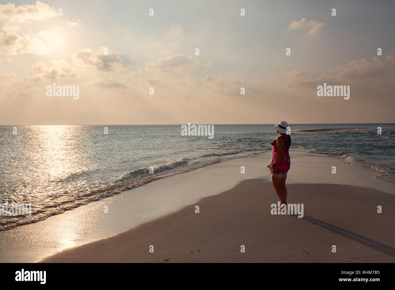 Malediven Urlaub - eine Frau touristische Blick auf den Sonnenuntergang über dem Indischen Ozean vom Strand, Konzept - Spielraum; Rasdhoo Atoll, Malediven Asien Stockfoto