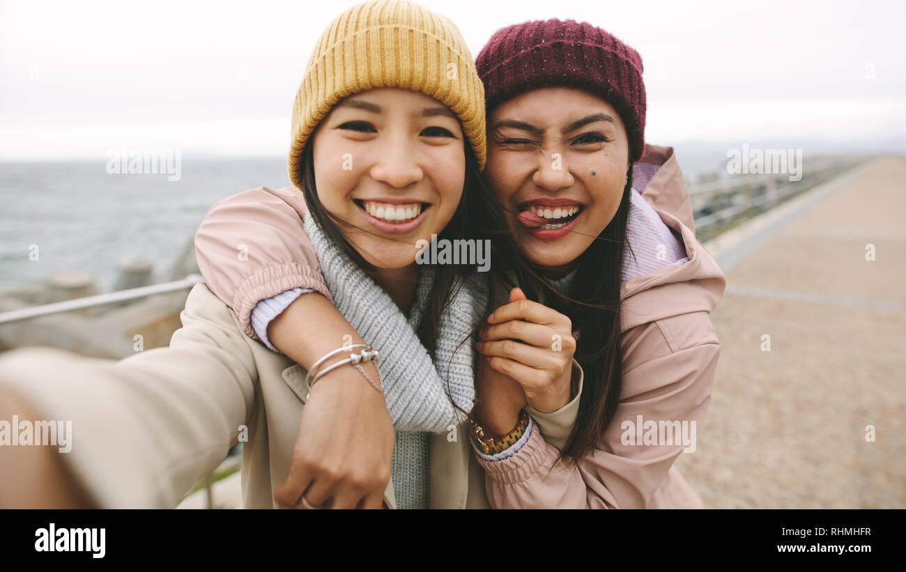 Lächelnd asiatische Frauen stehen im Freien jede andere Holding an einem Wintermorgen. Freundliche asiatische Frauen im Winter tragen Spaß, die Gesichter stehen Nea Stockfoto